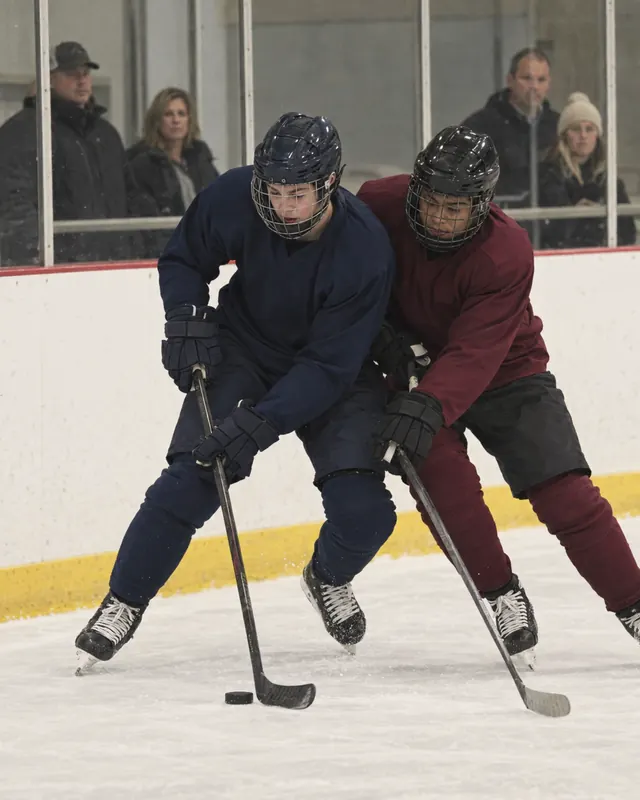 Youth hockey players chasing the puck along the boards